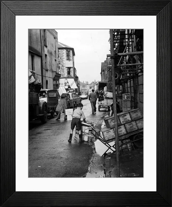 Framed Print : A busy street scene as traders, workmen and children go about their business