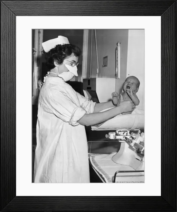Framed Print : A nurse pictured holding and weighing a baby December 1956 Framed Print : A nurse pictured holding and weighing a baby December 1956