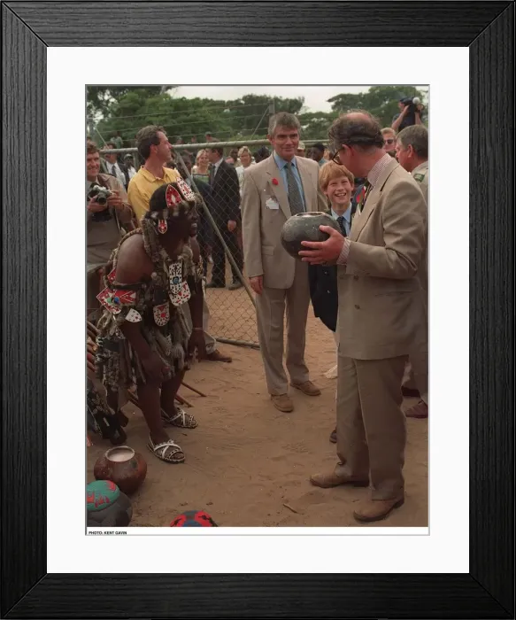 Framed Print : Prince Charles samples the native drink whilst his son Prince Harry watches on their Framed Print : Prince Charles samples the native drink whilst his son Prince Harry watches on their