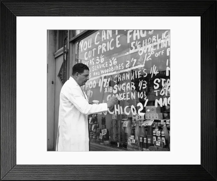 Framed Print : A Forest Gate grocer seen here painting his latest price reductions on the shop window
