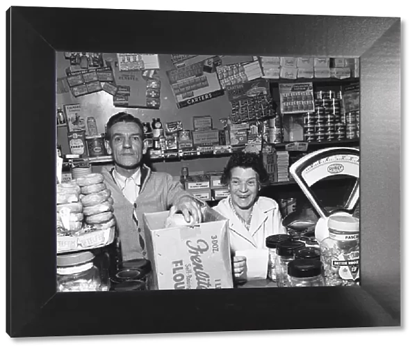 Local grocer and his wife seen here serving a customer. 14th November 1955