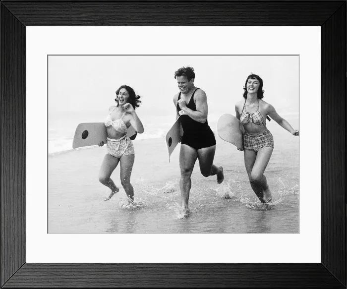 Framed Print : Seaside men and women run along sea shore in swimwear Unknown date