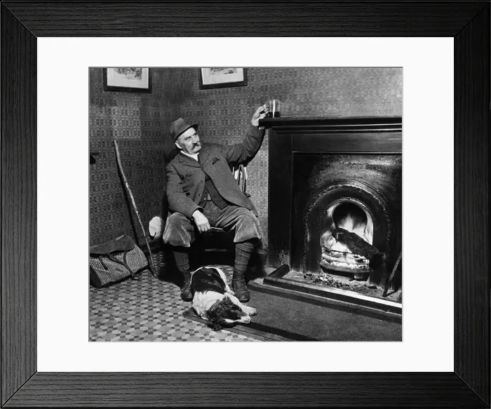 Framed Print : Man and his Dog - March 1935 A game keeper relaxes with his drink by the fire Framed Print : Man and his Dog - March 1935 A game keeper relaxes with his drink by the fire