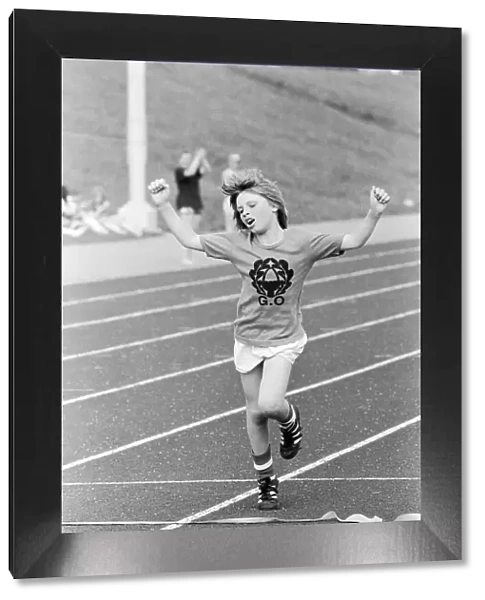 A young boy raises his arms in celebration as he crosses the finish line to win the race
