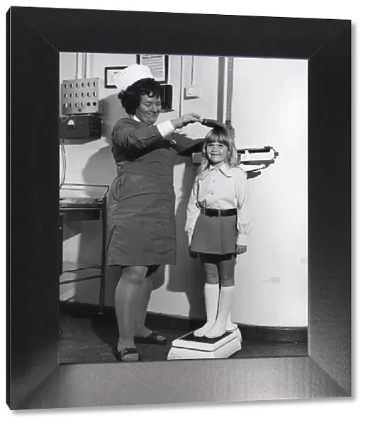 School nurse seen here measuring and weighing a pupil. 25th August 1972