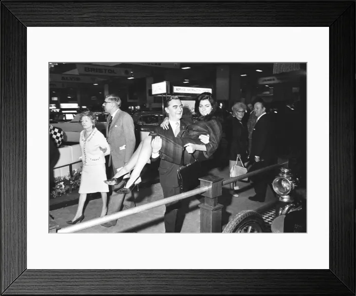 Framed Print : Model being helped over the barroer to a stand before she poses at the British Framed Print : Model being helped over the barroer to a stand before she poses at the British
