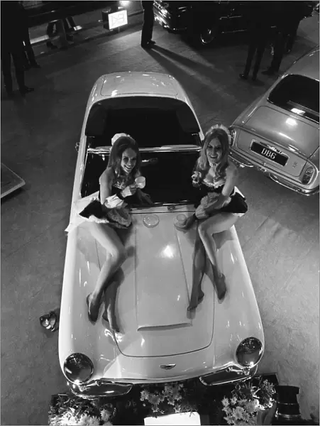 Models pose on the bonnet of a Aston Martin Volante at Motor Show 15th October 1968
