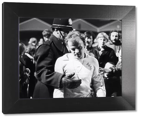 Leeds captain Billy Bremner leaves the field on the consoling arm of the law after his