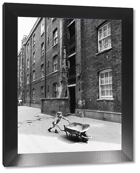 Two and a half year old Darren Haydn plays with his wheelbarrow outside the Great Eastern