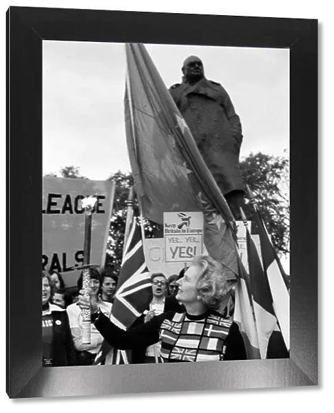 Mrs Margaret Thatcher holding the European flag under the statue of Sir Winston Churchill