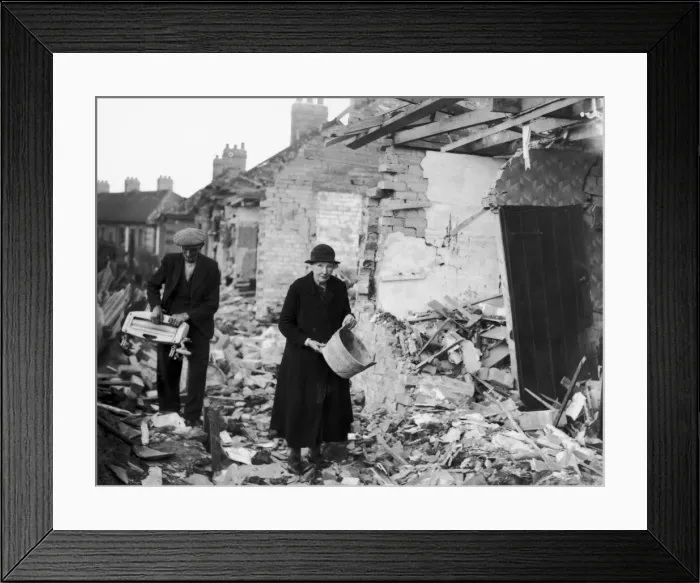 Framed Print : An elderly couple clear away the rubble near their homes after an air raid by the German