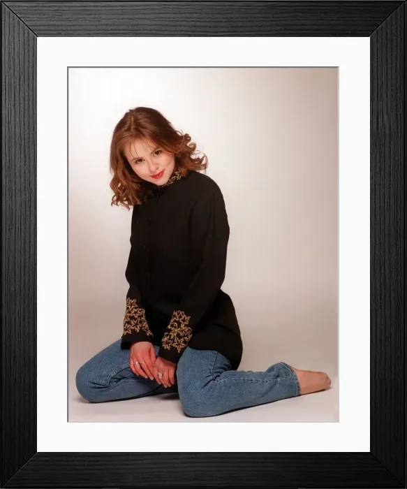 Framed Print : Catriona Evans kneeling wearing blue denims and black gold shirt blouse light brown