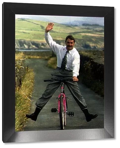 Nigel Mansell Formula One Racing Driver Riding A Bicycle Down A Country Lane
