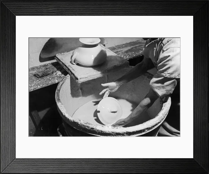Framed Print : A worker at the Minton China Works in Stoke On Trent, dips a newly created article into a Framed Print : A worker at the Minton China Works in Stoke On Trent, dips a newly created article into a