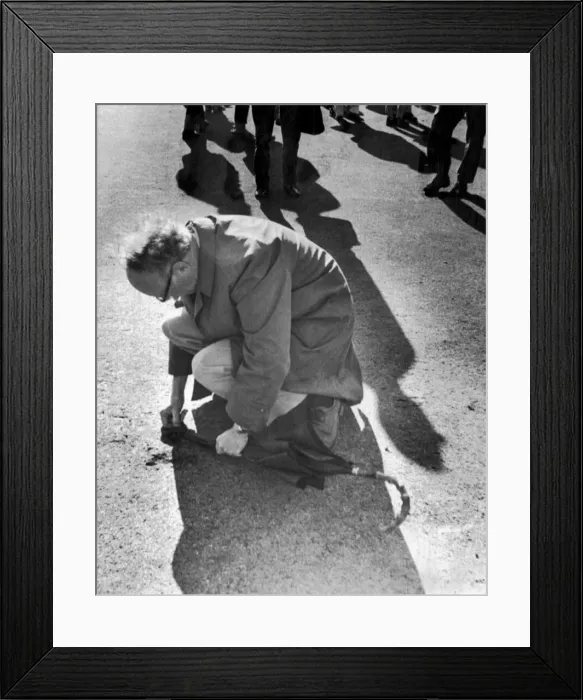 Framed Print : Man using his umbrella to prise up a piece of turf at Bramall Lane Framed Print : Man using his umbrella to prise up a piece of turf at Bramall Lane
