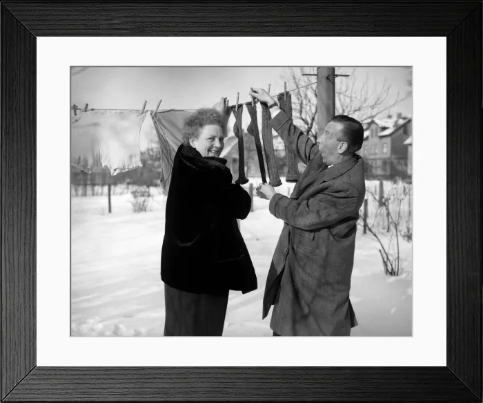 Framed Print : A couple hanging out their washing - socks, smiling in the snow 8th January 1955 Framed Print : A couple hanging out their washing - socks, smiling in the snow 8th January 1955