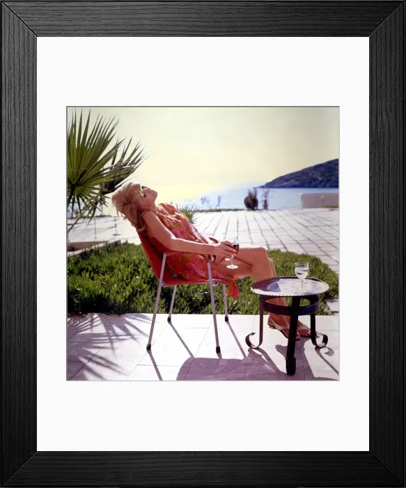 Framed Print : Melanie lost in her thoughts relaxes by the sea with a glass of red wine. Circa 1965 Framed Print : Melanie lost in her thoughts relaxes by the sea with a glass of red wine. Circa 1965