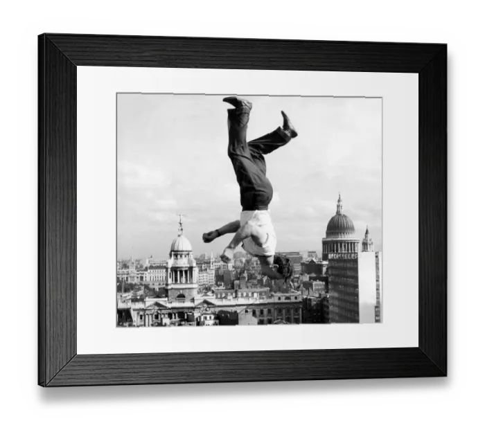 Framed Print : Acrobat Frank Paulo jumps upside down on a trampoline on the roof of the GPO building in