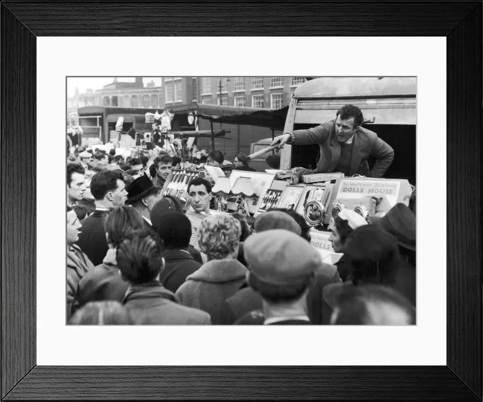 Framed Print : A stall holder at Petticoat Lane market serves another customer as crowds descended Framed Print : A stall holder at Petticoat Lane market serves another customer as crowds descended