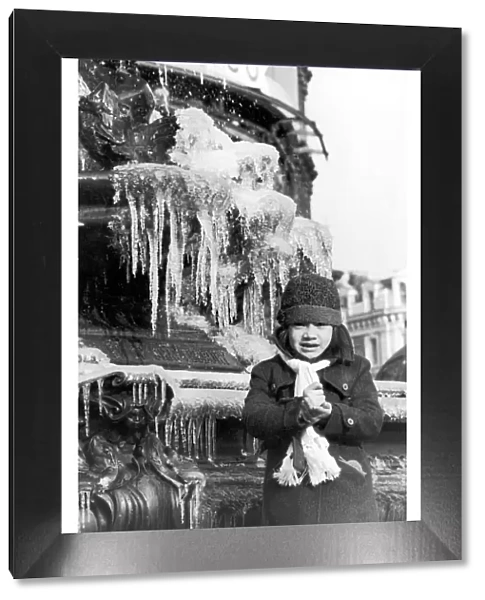 A young girl freezing cold, wrapped up in a coat, hat and scarf