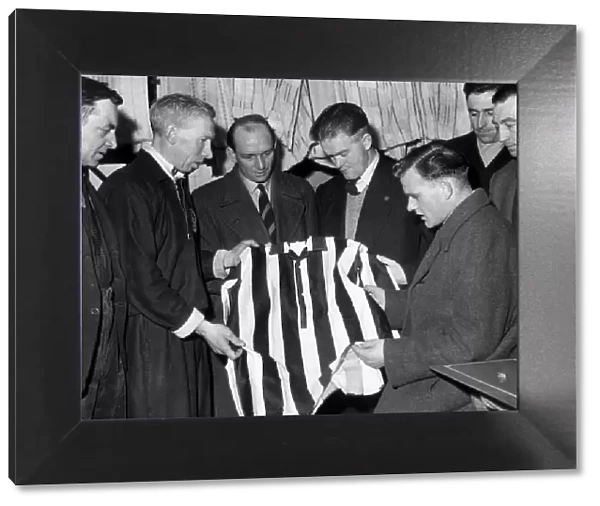 Scunthorpe United players & coaching staff examine shirt of local works team that they