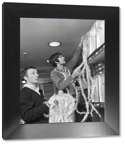 Footballers George Best and Mike Sumerbee make a start on the festive decorations at