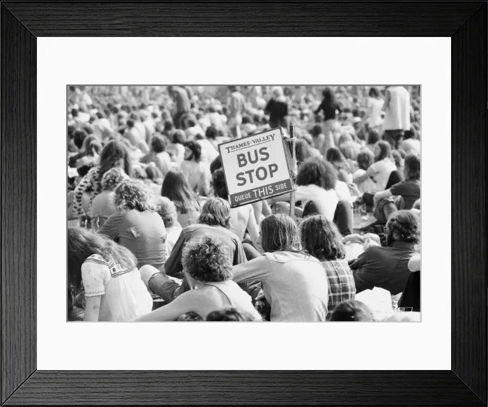 Framed Print : Reading Pop Festival. Festival goers with a Bus Stop sign watching the bands