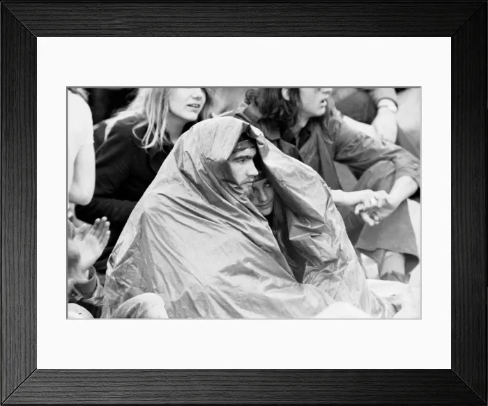 Framed Print : Reading Pop Festival. Young festival goers take cover from the rain under make Framed Print : Reading Pop Festival. Young festival goers take cover from the rain under make