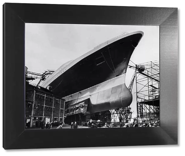 Ship builders playing football below the hull of the new Cunard Liner QE2 at Clyde