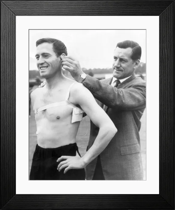Framed Print : Arsenal manager George Swindin attaches a receiver to left back Jimmy Bloomfield to try