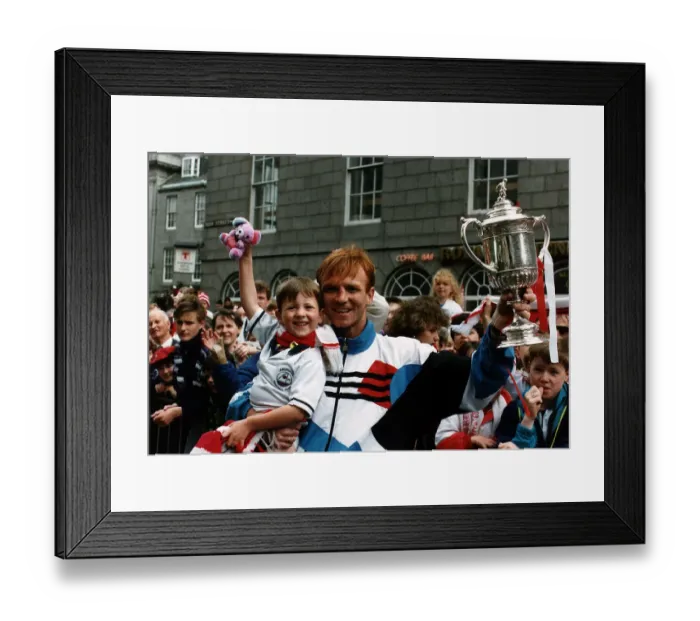 Framed Print : Alex McLeish of Aberdeen Football Club in the street holding up his son in one hand