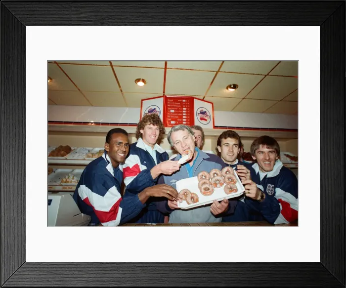 Framed Print : England manager Bobby Robson enjoying a selection of doughnuts with members of his Framed Print : England manager Bobby Robson enjoying a selection of doughnuts with members of his