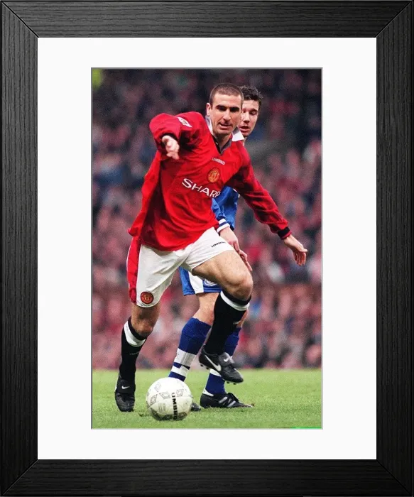 Framed Print : Eric Cantona fends off a Leicester defender during their match at Old Trafford Framed Print : Eric Cantona fends off a Leicester defender during their match at Old Trafford