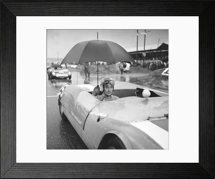 Framed Print : Brian Hart holds an umbrella up to keep off the heavy rain as he waits for the start of
