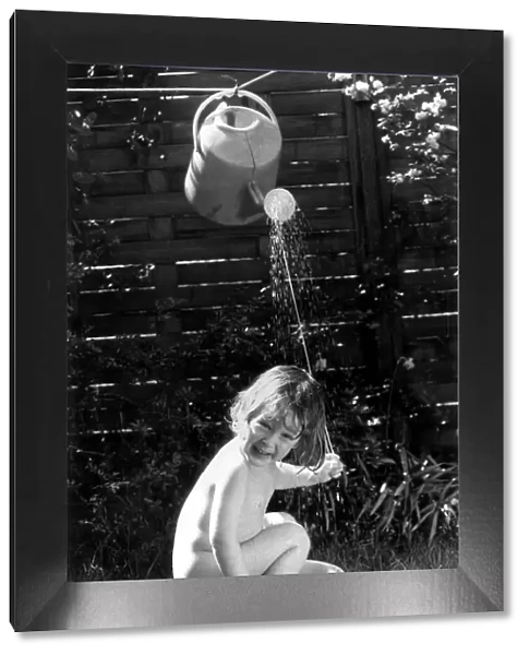 Three year old Tom Bardy is enjoying an improvised shower bath in the back garden of his