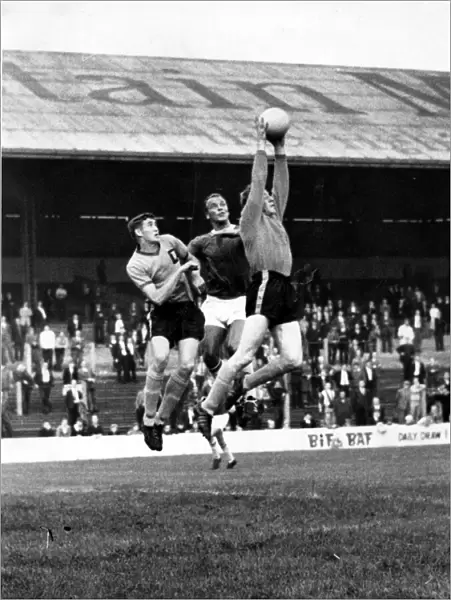 Len Weare, the Newport County goalkeeper jumps high to gather the ball under pressure