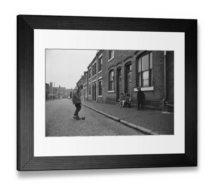 Framed Print : Two asian boys playing football in the street while their friends look on in Marshall