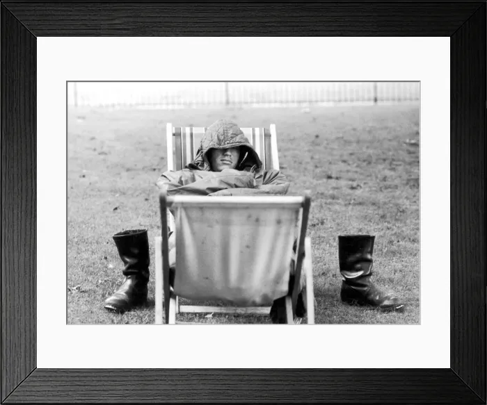 Framed Print : A weary traveller removes his boots as he takes a rest on a bed made from two deckchairs Framed Print : A weary traveller removes his boots as he takes a rest on a bed made from two deckchairs