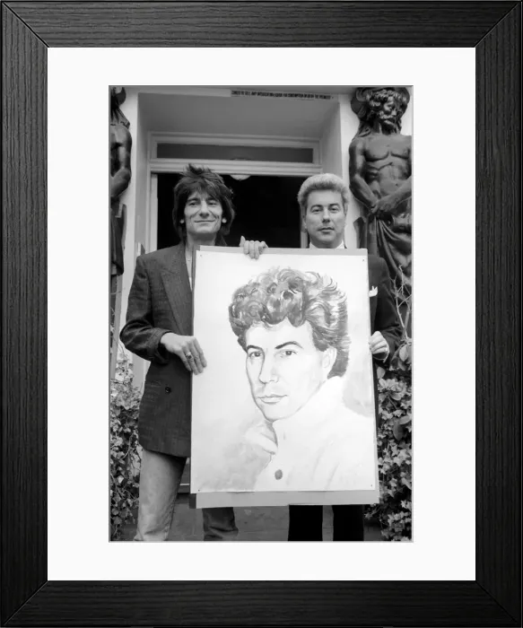 Framed Print : Rolling Stones: Ronnie Wood holds a painting of author Ken Follett who stands next to him