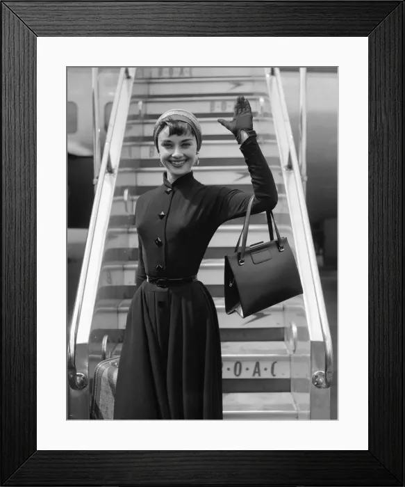 Framed Print : Film actress Audrey Hepburn waves as she stands in front of the steps of her plane Framed Print : Film actress Audrey Hepburn waves as she stands in front of the steps of her plane