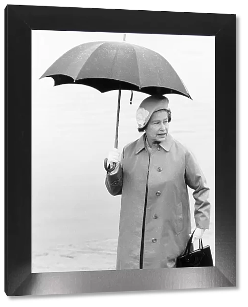 Her Majesty Queen Elizabeth II holding an umbrella in the rain. 10th August 1984