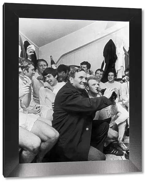 Leeds United manager Don Revie holds a bottle of champagne for captain Billy Bremner