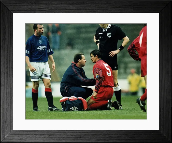 Framed Print : John Inglis of Aberdeen kneeling on ground being treated by a physio after a headbutt by