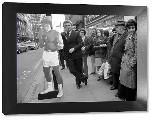 Boxer Joe Bugner waiting at a bus stop with a life size cut out of Mohammad Ali on his