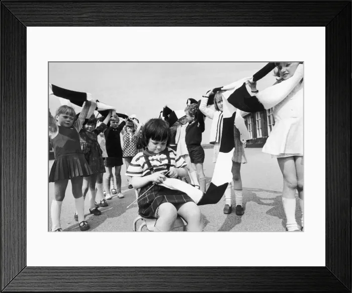 Framed Print : Little Wendy Scorer knits busily away. Her friends look on as a long scarf grows even Framed Print : Little Wendy Scorer knits busily away. Her friends look on as a long scarf grows even