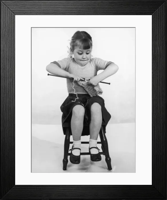 Framed Print : A young girl concentrating on her knitting, biting her lip sticking her elbows well out Framed Print : A young girl concentrating on her knitting, biting her lip sticking her elbows well out