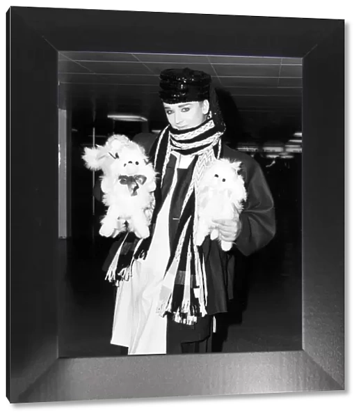 Singer Boy George arrives at Heathrow airport carrying two furry toy animals wearing