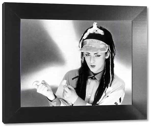 Singer Boy George with hair extensions wearing a cap with his name on it