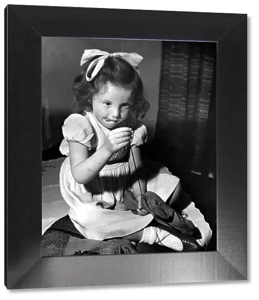 Little Hazel Robson of Newcastle, has a go at repairing a hole in a sock