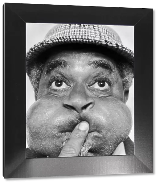 American jazz musician Dizzy Gillespie puffing out his cheeks during a visit to